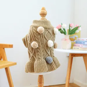 Close-up of pet knit sweater featuring cable patterns, colorful pom-poms and ruffled hem