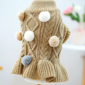 Macro shot of khaki cable knit pet sweater with decorative pompoms and ruffled hem detail