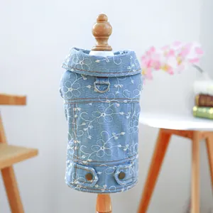 Gilet di jeans azzurro per cani con ricami floreali e anello a D su modello in legno