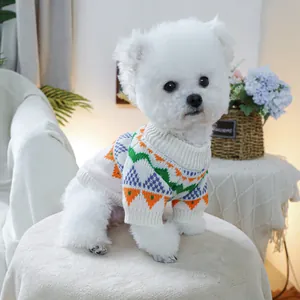 Detail of soft knit pet sweater featuring colorful geometric patterns on a white puppy
