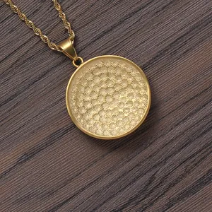 Macro shot of gold stainless steel rope chain and circular pendant on wooden background