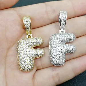 Dettaglio dei ciondoli lettera F stile hip hop in oro e argento con pavé di zirconi