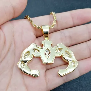 Dettaglio macro del ciondolo braccio muscoloso dorato con catena rope e zirconi