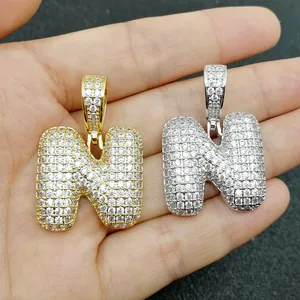Dettaglio di ciondoli lettera N a bolla argento e oro con zirconi micro-pave in mano