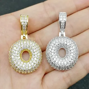 Dettaglio macro di ciondoli in oro e argento con zirconi bianchi micro-pavimentati