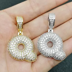 Dettaglio di ciondoli a lettera Q in oro e argento con pavé di zirconi scintillanti