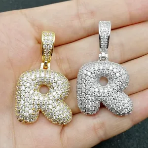 Vista macro dei ciondoli a lettera R in oro e argento con micro-pave di zirconi cubici