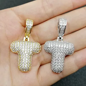 Dettaglio macro dei ciondoli a bolla lettera T in oro e argento con pietre di zircone
