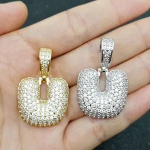 Vista macro di ciondoli con lettere a bolla in oro e argento con zirconi micro-pave
