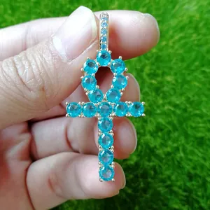 Detailed view of the blue zircon encrusted Ankh cross pendant held in hand outdoors