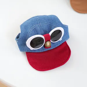 Detailed close-up of blue denim pet sun hat with red visor and decorative mini sunglasses