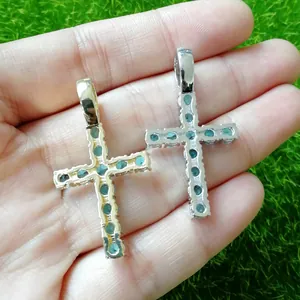 Close-up of gold and silver Ankh cross pendants with blue zircon stones held in hand