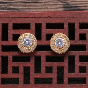 Macro shot of gold hip hop stud earrings with pave-set zircon stones on wood surface