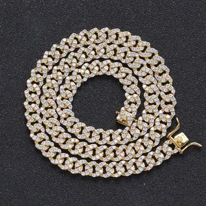 Macro detail of 8mm gold Cuban link chain with paved cubic zirconia on black surface