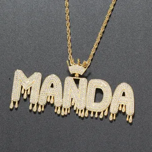 Détail du pendentif MANDA doré avec couronne et effet goutte, serti de pierres brillantes