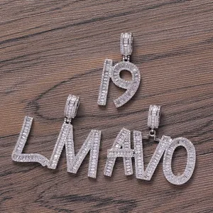 Close-up of iced out silver pendant with baguette and round zircons on wood surface