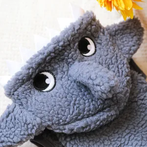 Détail d'un sweat à capuche monstre en polaire grise avec de grands yeux et dents en feutre