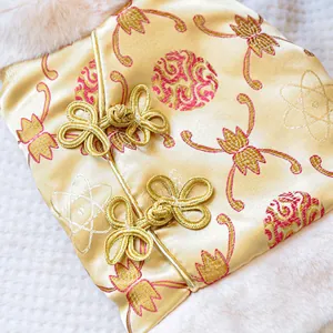 Detail of traditional Chinese pet outfit with gold satin, floral patterns and frog buttons