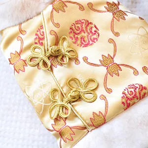 Detailed macro view of gold silk pet dress with red floral embroidery and frog buttons