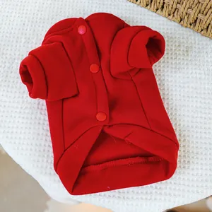 Detail der roten Haustier-Strickjacke mit Druckknöpfen auf weißer Kuscheldecke