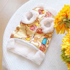 Detail of pet winter vest featuring golden brocade fabric and warm white faux fur lining