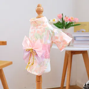 Detail of pink floral pet kimono with large bow and golden tassels on a wooden hanger