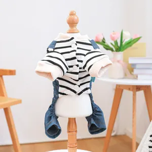 Dettaglio di camicia a righe per animali con salopette di jeans e bottoni su manichino legno