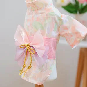 Detailed close-up of a Japanese pet kimono featuring floral patterns and a pink bow with tassels