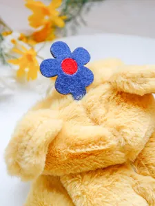 Detailed macro view of soft yellow plush fabric with a decorative blue and red felt flower