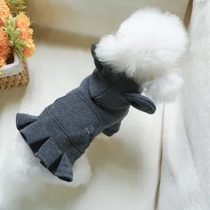Detail of grey hooded pet dress with white D embroidery and pleated hem on a soft sofa