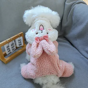 Pink and white plush dog onesie with cartoon bunny ears and bow detail on sofa