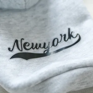 Macro shot of high-quality heather grey dog hoodie fabric with New York print detail