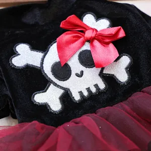 Detail of pet dress showing black velvet fabric, skull patch, and red mesh skirt