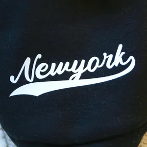Close-up of black pet hoodie featuring white Newyork calligraphy print and cotton texture