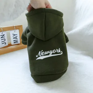 Detail view of dark green fleece pet hoodie with white Newyork print on a textured background