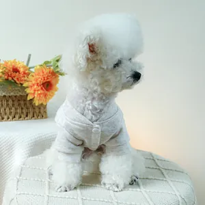 Close-up of oatmeal knit dog cardigan with button closure on a Bichon Frise