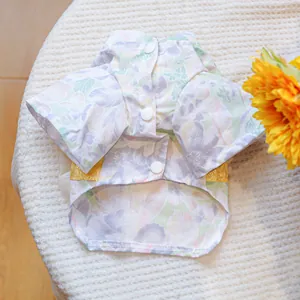 Detailed close-up of floral pet shirt with gold lace trim and white buttons on knit surface
