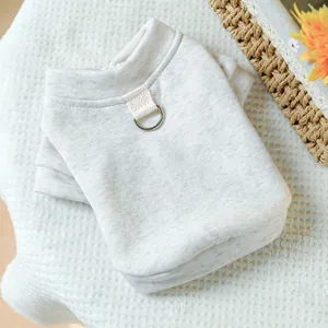 Close-up of beige knit pet vest with a metal D-ring for leash attachment on waffle fabric