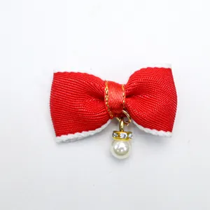 Close-up of red bow pet hair clip with faux pearl pendant and sparkling rhinestones