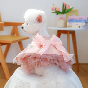 Close-up of pink pet dress featuring a large bow and layered lace tutu on a small dog