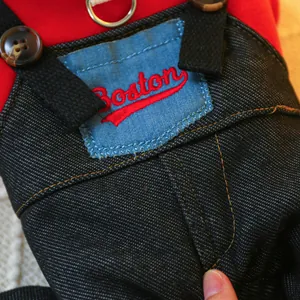 Close-up of pet denim overalls featuring red Boston embroidery and vintage buttons