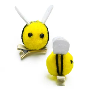 Detail view of cute bee hair clips with yellow plush balls and metal duckbill clips