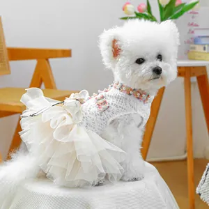 Close-up of white pet lace dress with 3D handmade flowers and pearls on a small dog