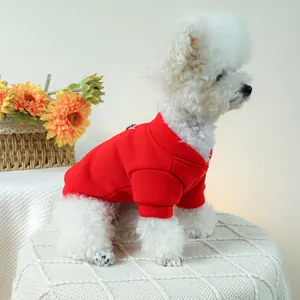 Red pet sweater with harness hole shown on a white dog in a warm, cozy setting