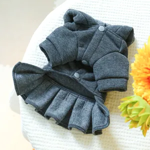 Detail of dark grey pet knit dress with snap buttons and pleated skirt on white textile