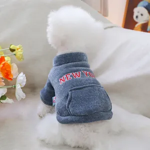 Dettaglio felpa blu in maglia per cani con ricamo New York su un piccolo cane bianco