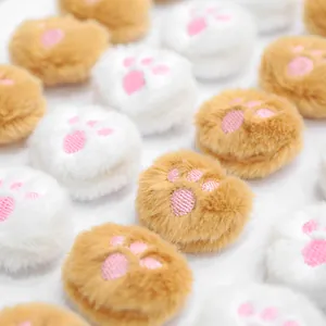 Close-up of plush cat paw accessories with pink embroidery for pet hair clips