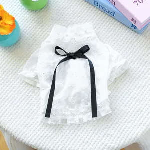 Detail of white daisy embroidery pet shirt with ruffles and a black ribbon pearl bow