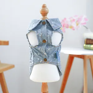 Dettaglio del gilet in denim azzurro per animali con ricami floreali bianchi e bottoni