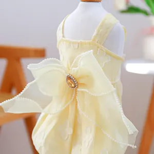 Detailed close-up of yellow pet dress featuring large bow with pearl and gem accents